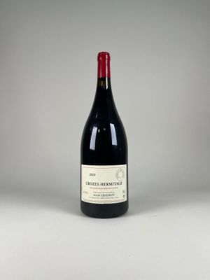 a bottle of red wine sitting on top of a white table