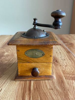 an old coffee grinder sitting on top of a wooden table