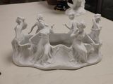 a white sculpture of a group of people on a table
