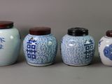 four blue and white vases are lined up against a gray background