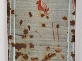 rusted metal plate with a red flower on it on a white surface