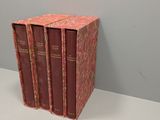 trois livres rouges posés sur une table blanche, près d'un mur gris