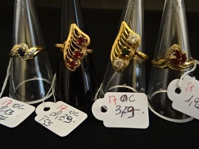 cinq bagues différentes, accompagnées de leurs étiquettes de prix, posées sur une table