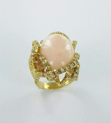 un gros plan d'une bague ornée d'une pierre rose entourée de diamants