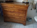 une commode en bois dans une salle de bains, avec un miroir au-dessus