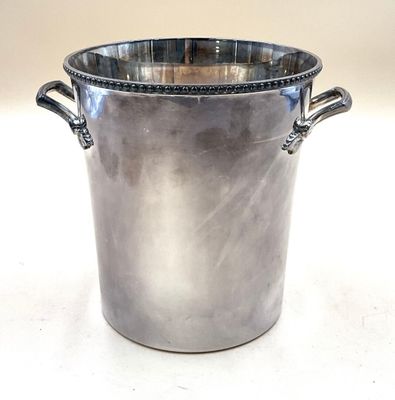 une grande casserole en métal à deux poignées posée sur une surface blanche