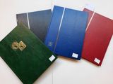 quatre cahiers de couleurs différentes posés sur une table blanche