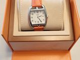 une boîte orange contenant une montre, posée sur une surface blanche