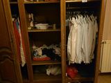 une armoire en bois sur laquelle sont posés des vêtements, dans une pièce