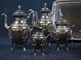 five silver teapots and a tray on a blue background