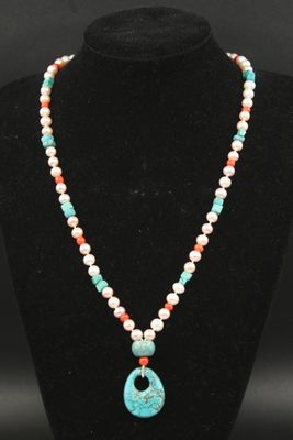 un collier avec un pendentif en turquoise et en pierre rouge sur un mannequin noir