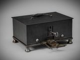 an old black metal box with a key on top of it