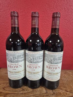 trois bouteilles de vin rouge sont posées sur une table devant un mur rouge