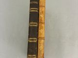 deux livres anciens posés sur une étagère, dont l'un est tenu par une main