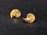 a pair of gold earrings on a black surface