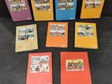 six books of children ' s comics are lined up on a black surface