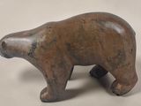 a small wooden bear that is standing on a white surface