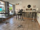 tables and chairs in a restaurant with a clock on the wall