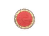 un gros plan d'une bague rouge et dorée sur fond blanc