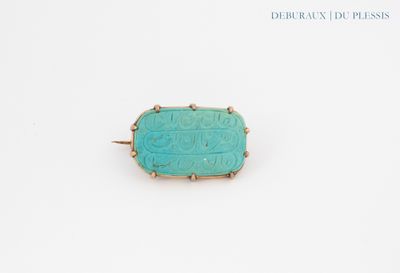 a turquoise stone ring with gold accents on a white surface