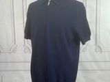 un polo bleu marine posé sur un mannequin devant un mur blanc