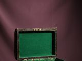 an old wooden box with a green lid sitting on a purple surface