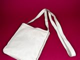 the white bag is sitting on a pink surface