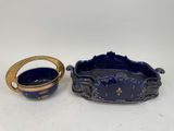 a blue and gold bowl and a gold ring on a white surface