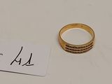 une bague en or et une étiquette posées sur une table blanche