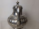 a silver tea pot sitting on a glass table