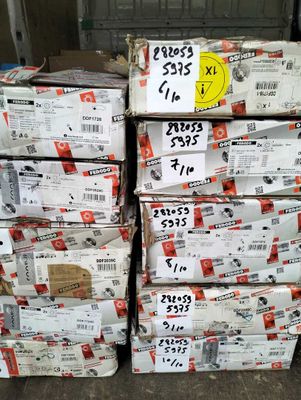 Plusieurs piles de cartons sont empilées les unes sur les autres dans un entrepôt.