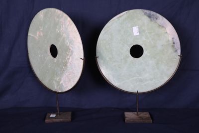 paire de grandes sculptures en forme de disques en jade vert, posées sur des socles, sur fond bleu