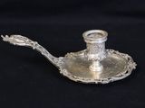 a silver candle holder with a spoon on it