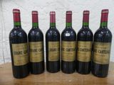 six bouteilles de vin sont alignées sur une table en bois