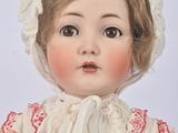 a close up of a doll wearing a white dress and bonnet