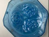 a blue glass plate with four blue roses on it