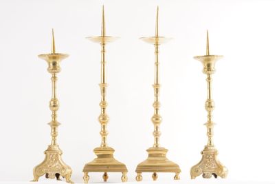 trois chandeliers dorés posés les uns à côté des autres sur une surface blanche