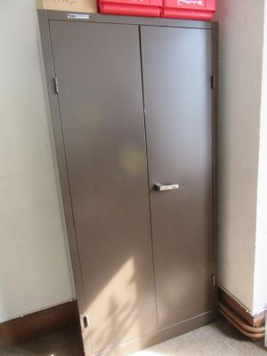 une armoire métallique placée dans un coin de la pièce, sur laquelle se trouve une poubelle rouge