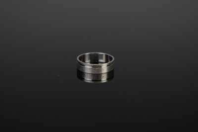 gros plan d'une bague en argent sur une surface noire