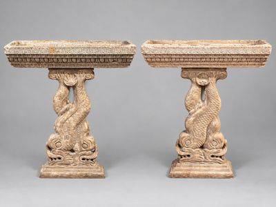 une paire de socles en pierre sculptée sur lesquels figurent un poisson et un serpent