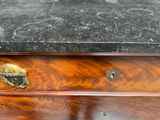 a wooden chest of drawers with a black marble top