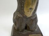 une statue représentant un ours assis sur un socle en bois
