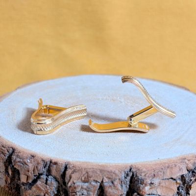 une paire de boucles d'oreilles en or posée sur une souche d'arbre