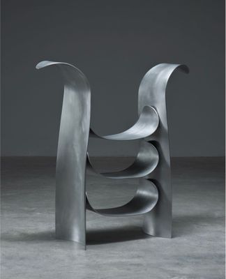 une sculpture métallique abstraite dans une pièce sombre, sur fond gris
