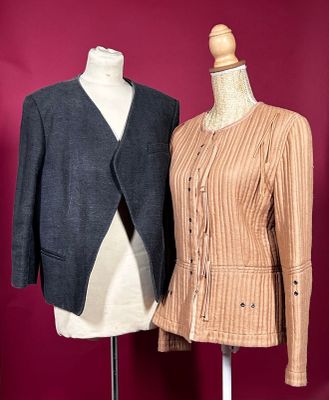 two women ' s jackets on a mannequin stand against a red wall