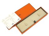 an orange box with a pair of earrings in it on a white surface