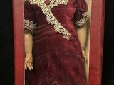 an image of a doll in a red box on a black surface