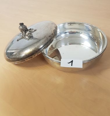 un petit bol en argent avec un couvercle posé sur une table