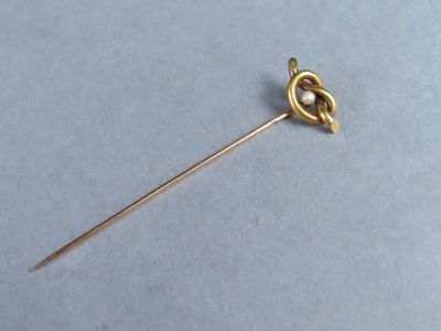 une broche en or ornée d'un nœud, sur un fond bleu