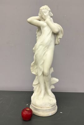 statue d'une femme tenant une pomme rouge posée sur une table